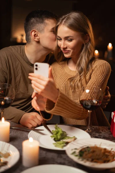 Young couple in love having dinner at restaurant romantic date taking selfie using smartphone. Copy space