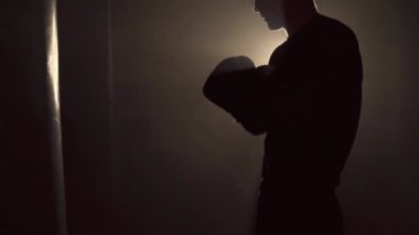 Eldiven takan bir boksör kum torbasına vurmaya hazırlanıyor. Boksör eğitim konsepti. Boşluğu kopyala