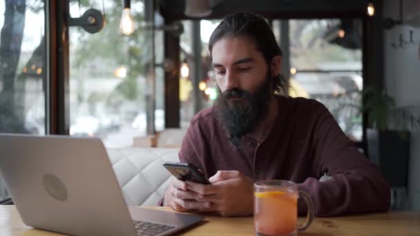 Hombre Barbudo Guapo Leyendo Notificación Teléfono Inteligente Sentado Con Ordenador — Vídeos de Stock