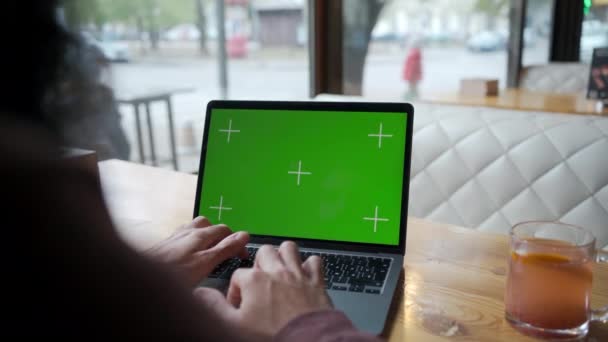 コンセプト リモートワーク フリーランス ラップトップで作業 モニターの緑色のスクリーンでラップトップを使用してカフェで働くマンフリーランサー リアビュー コピースペース — ストック動画