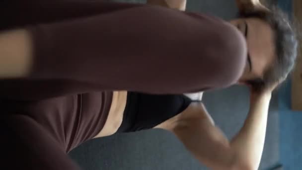 年轻女人在体育馆里锻炼 鼓起她的腹肌 紧张她的腹部肌肉 扭曲她的身体来减肥 垂直录像 — 图库视频影像