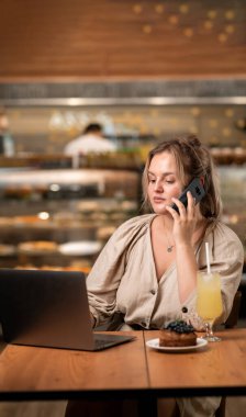 Bilgisayarla uzaktan yakından ilgilenen genç serbest çalışan ve içerideki kafedeki amiriyle telefonda gülümseyen biri. Boşluğu kopyala