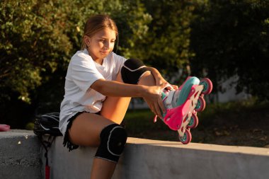 Yazın açık havada bir parkta otururken çocuk patenler giyiyordu. Boşluğu kopyala