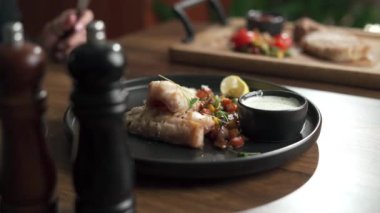 Sebzeli ve soslu levrek fileto. Kadınlar masada oturarak lezzetli ve sağlıklı yiyecekler yiyorlar, yakından. Bir restoranda öğle yemeği. Farklı yemekleri olan restoran menüsü. Boşluğu kopyala