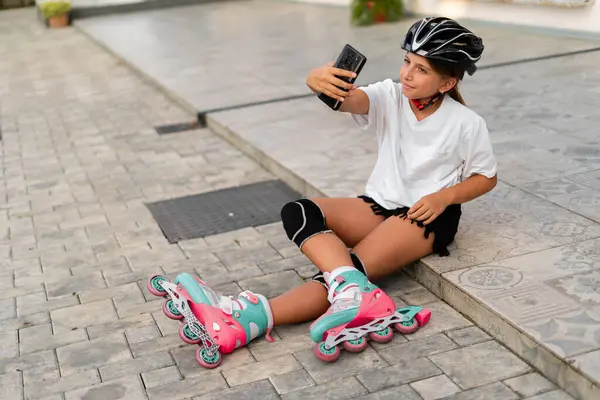 Child girl roller skating, make selfie and filming video of herself for sharing on social media. Copy space