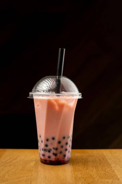 Siyah arka planda plastik bardakta çilekli köpük çayı. Boşluğu kopyala