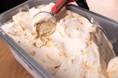 Vanilyalı karamelli dondurmayı konteynırdan kepçeleme, üst manzara. Dondurma, düz yat. Boşluğu kopyala