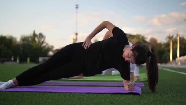 Gruppe Von Sportlerinnen Macht Seitenplanken Gymnastik Den Körper Auf Grünem — Stockvideo