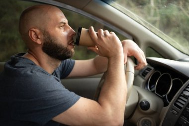 Milenyum adamı direksiyon başındayken araba kullanır ve kahve içer. Boşluğu kopyala