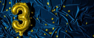 Mavi kadifede üç numaralı altın folyo balonu. Doğum günü tebrik kartı ve 3. yazı. Altın sayılar ve kumaş arka plan. Işıltılı sayısal rakam. Pankart. Boşluğu kopyala