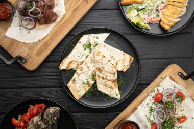 Izgarada kızartılmış Gürcü mutfak yemekleri, peynirli kebap ve pita ekmeği, bir restorandaki ahşap masada servis edilen tabaklar. Boşluğu kopyala