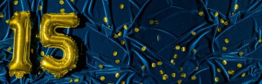 15 numara, altın folyo balon numarası mavi kadife arka planda konfetili. Doğum günü tebrik kartı, 15. yazı. Yıldönümü etkinliği. Pankart. Şık altın rakamlı, parlak parlak bir ışık. Boşluğu kopyala,