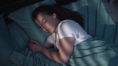 Genç barışçıl kadın geceleri yatağında uyuyor dinleniyor ve dinleniyor. Boşluğu kopyala