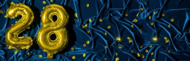 28 numara, altın folyo balon numarası mavi kadife arka planda, konfetiyle birlikte. Doğum günü tebrik kartı, 28. yazı. Yıldönümü etkinliği. Pankart. Şık altın rakamlı, parlak parlak bir ışık. Boşluğu kopyala,