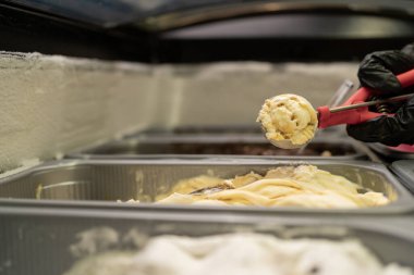 Bir pazarlamacının elleri bir şekerleme dükkanının vitrininde dondurma topluyor. Yaz ve tatlı konsepti