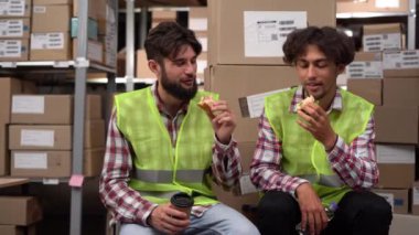 Depo çalışanları iş yerinde yemek yiyor, iletişim kuruyor ve sandviç yiyorlar. Boşluğu kopyala