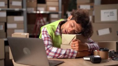 Fazla çalışan erkek çalışanlar iş başında uyuyup dinleniyorlar. Depoda paketlerle oturan genç tembel işçi. Boşluğu kopyala
