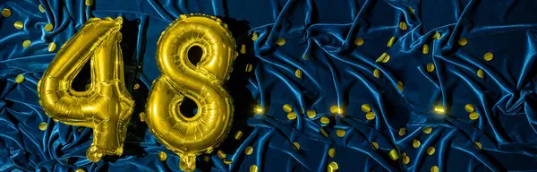 number forty eight, gold foil balloon number on a blue velvet background with confetti. Birthday greeting card, inscription 48. Anniversary event. Banner. Stylish gold numeral, bright shiny shine.