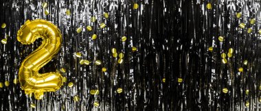 Siyah süslemenin arka planında 2 numaralı altın folyo balonu. Doğum günü tebrik kartı, ikinci yazı. Yıldönümü etkinliği. Pankart. Boşluğu kopyala.
