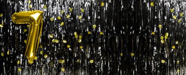 Siyah süslemenin arka planında 7 numaralı altın folyo balonu. Doğum günü tebrik kartı, yedinci yazı. Yıldönümü etkinliği. Pankart. Boşluğu kopyala.