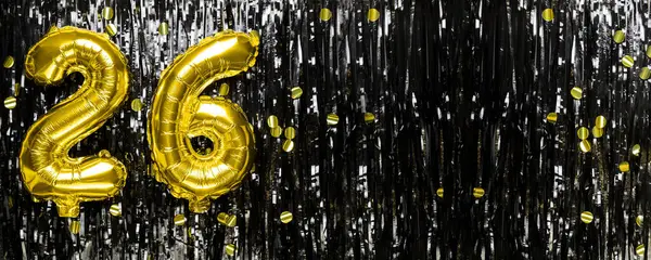 Gold foil balloon number number 26 on a background of black tinsel decoration. Birthday greeting card, inscription twenty six. Anniversary event. Banner. copy space.