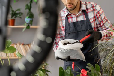 Erkek bahçıvan telefonda bitkilerden bahsediyor. Blogger internet blogu için ev bahçesinde çalışırken akıllı telefondan video çekiyor. Yakın plan.