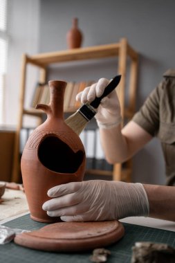 Arkeolog, eski vazo ve fırçayla geç saatlere kadar ofiste çalışıyor. Boşluğu kopyala