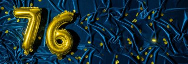 Mavi kadife dekorasyonun arka planında 76 numaralı altın folyo balonu. Doğum günü tebrik kartı, yazıt yetmiş altı. Yıldönümü etkinliği. Pankart. Boşluğu kopyala