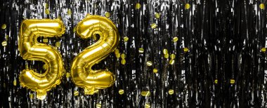 Altın folyo balon numarası 52 siyah süsleme arka planında. Doğum günü tebrik kartı, yazıt elli iki. Yıldönümü etkinliği. Pankart. Boşluğu kopyala.