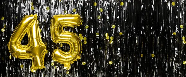Gold foil balloon number number 45 on a background of black tinsel decoration. Birthday card, inscription forty-five. Anniversary event. Banner. copy space.