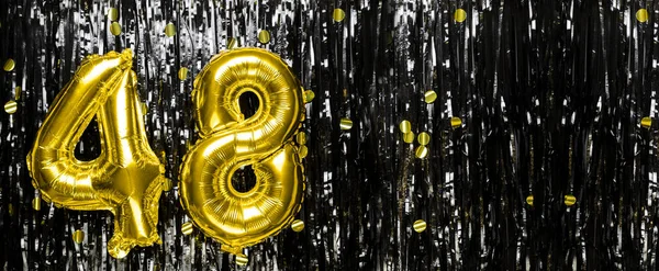Gold foil balloon number number 48 on a background of black tinsel decoration. Birthday card, inscription forty-eight. Anniversary event. Banner. copy space.