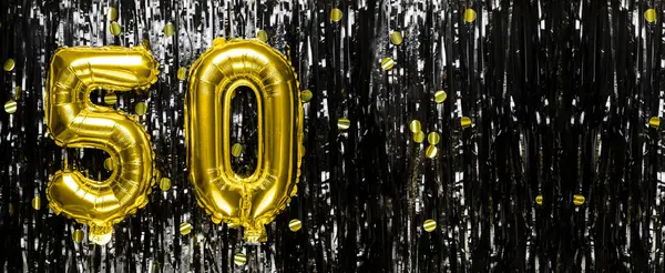 Gold foil balloon number number 50 on a background of black tinsel decoration. Birthday greeting card, inscription fifty. Anniversary event. Banner. copy space.