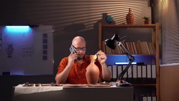 Erkek Arkeolog Gece Geç Saatlerde Ofiste Çalışıyor Arkadaşlarını Telefonla Arıyor — Stok video
