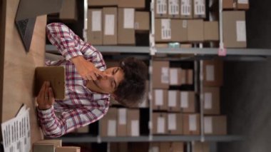 Depoda raflarla dolu bir tableti olan küçük bir işletme sahibi. Lojistikte çalışıyorum. Dikey video