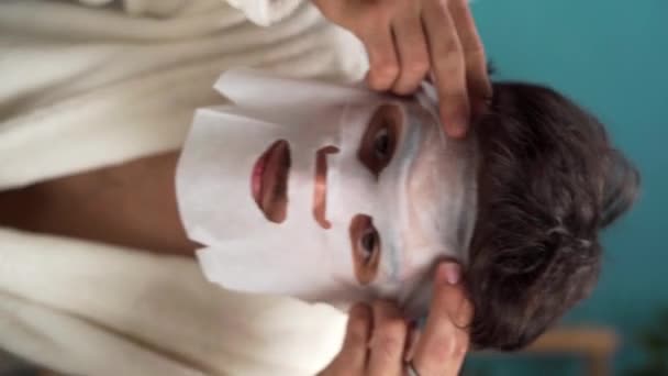 年轻人在脸上戴上白色的口罩 早上护肤 男性化妆品 美感和生活方式的概念 垂直录像 — 图库视频影像