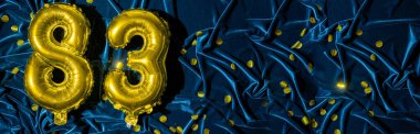 Seksen üç numaralı altın folyo balonu. Doğum günü ya da yıldönümü kartında 83 yazılıydı. Mavi kadife arka plan. Yıldönümü kutlaması. Pankart. Boşluğu kopyala