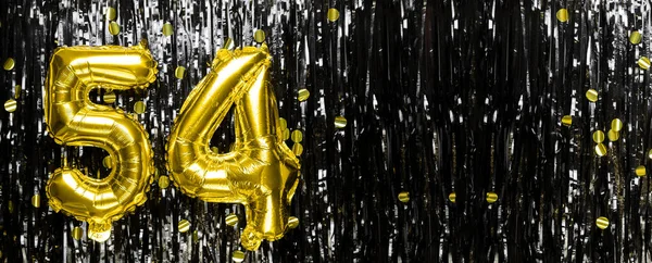 Gold foil balloon number number 54 on a background of black tinsel decoration. Birthday card, inscription fifty-four. Anniversary event. Banner. copy space.