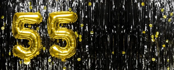 Gold foil balloon number number 55 on a background of black tinsel decoration. Birthday card, inscription fifty-five. Anniversary event. Banner. copy space.