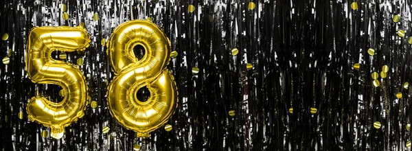 Gold foil balloon number number 58 on a background of black tinsel decoration. Birthday card, inscription fifty-eight. Anniversary event. Banner. copy space.