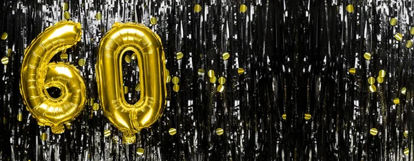 Gold foil balloon number number 60 on a background of black tinsel decoration. Birthday greeting card, inscription sixty. Anniversary event. Banner. copy space.