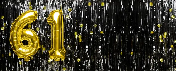 Gold foil balloon number number 61 on a background of black tinsel decoration. Birthday greeting card, inscription sixty-one. Anniversary event. Banner. copy space.