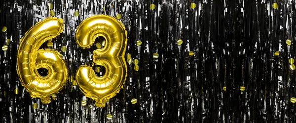 Gold foil balloon number number 63 on a background of black tinsel decoration. Birthday greeting card, inscription sixty-three. Anniversary event. Banner. copy space.