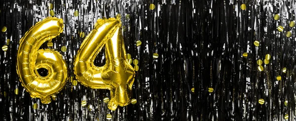 Gold foil balloon number number 64 on a background of black tinsel decoration. Birthday greeting card, inscription sixty-four. Anniversary event. Banner. copy space.