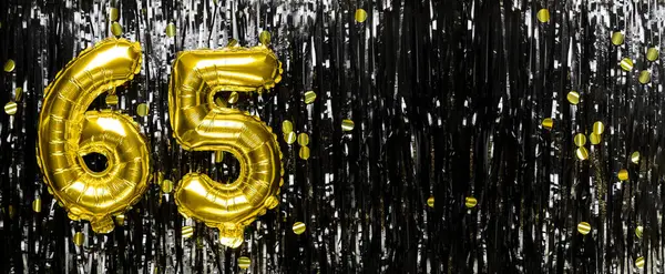 Gold foil balloon number number 65 on a background of black tinsel decoration. Birthday greeting card, inscription sixty-five. Anniversary event. Banner. copy space.