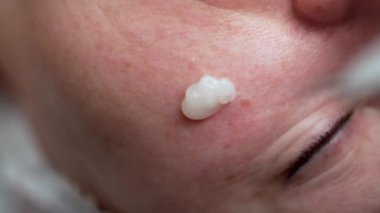 Güzellik salonunda yaşlanmayı önleyici kozmetik prosedür, yakın plan. Kozmetik uzmanı cildini nemlendirmek için kadın yüzüne jöle sürüyor. Maske takan bir güzellik uzmanı. Boşluğu kopyala