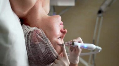 Kozmetik uzmanı ultrasonik temizlik yapıyor ve kaplıca merkezindeki kadının yüzünü tazeliyor. Dikey video