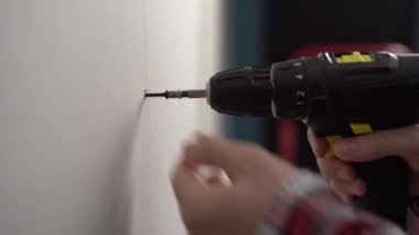 Erkek elinin yakın çekimi metal profile alçıpan takmak için elektrikli tornavida kullanıyor. Boşluğu kopyala