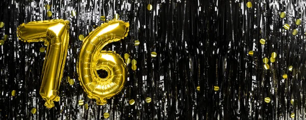 Gold foil balloon number number 76 on a background of black tinsel decoration. Birthday greeting card, inscription seventy-six. Anniversary event. Banner. copy space.