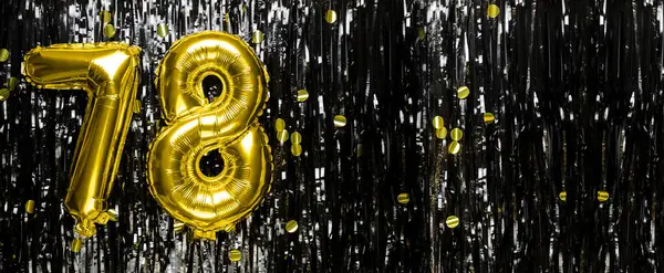 Gold foil balloon number number 78 on a background of black tinsel decoration. Birthday greeting card, inscription seventy-eight. Anniversary event. Banner. copy space.