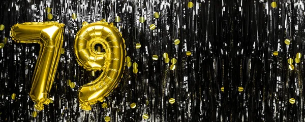 Gold foil balloon number number 79 on a background of black tinsel decoration. Birthday greeting card, inscription seventy-nine. Anniversary event. Banner. copy space.